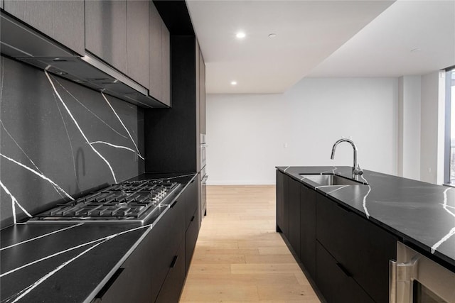 44 E Ave Unit 3203, Austin, TX 78701 - kitchen with a sink, light wood-style floors, wine cooler, stainless steel gas cooktop, and dark cabinets