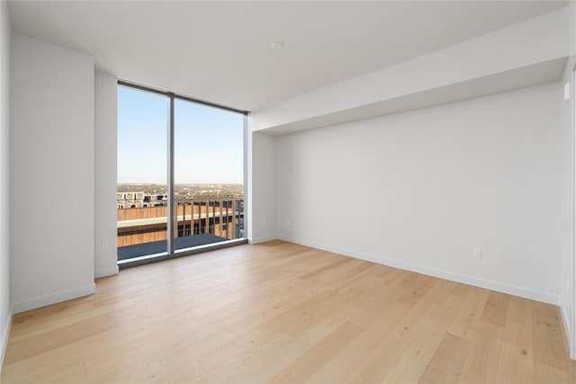 44 E Ave Unit 3203, Austin, TX 78701 - spare room featuring floor to ceiling windows, light wood-style floors, and baseboards