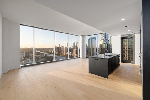 44 E Ave Unit 3203, Austin, TX 78701 - kitchen with floor to ceiling windows, a sink, dark cabinetry, light wood-style floors, and a view of city