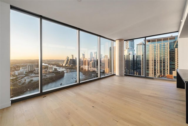 44 E Ave Unit 3203, Austin, TX 78701 - empty room featuring a view of skyline, wood finished floors, and a wall of windows