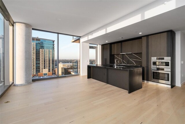 44 E Ave Unit 3203, Austin, TX 78701 - kitchen with double oven, dark countertops, modern cabinets, light wood finished floors, and floor to ceiling windows