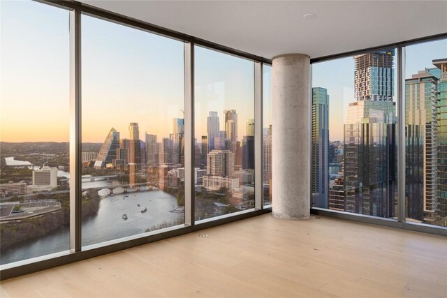 44 E Ave Unit 3203, Austin, TX 78701 - empty room featuring floor to ceiling windows, a skyline view, wood finished floors, and a water view