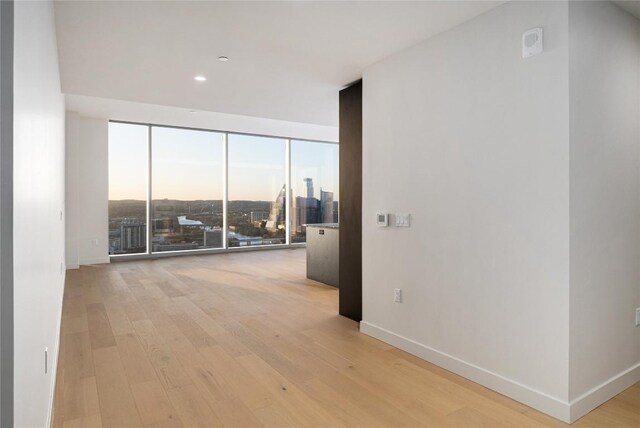 44 E Ave Unit 3203, Austin, TX 78701 - empty room with floor to ceiling windows, light wood-style flooring, baseboards, and a city view