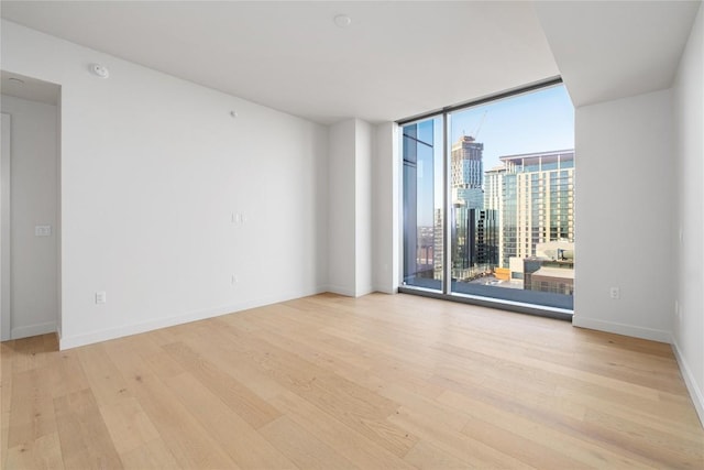 44 E Ave Unit 3203, Austin, TX 78701 - empty room featuring floor to ceiling windows, wood finished floors, a city view, baseboards, and a smoke detector