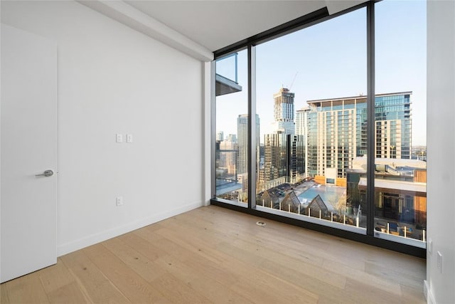 44 E Ave Unit 3203, Austin, TX 78701 - unfurnished room with expansive windows, healthy amount of natural light, wood finished floors, a view of city, and baseboards