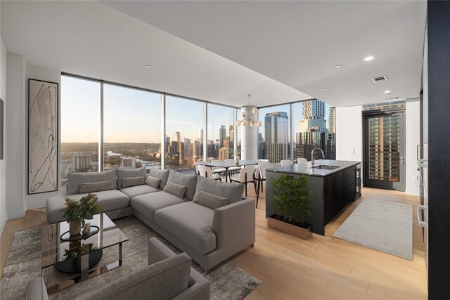 44 E Ave Unit 3203, Austin, TX 78701 - living area featuring light wood finished floors, a view of skyline, a wall of windows, a chandelier, and plenty of natural light