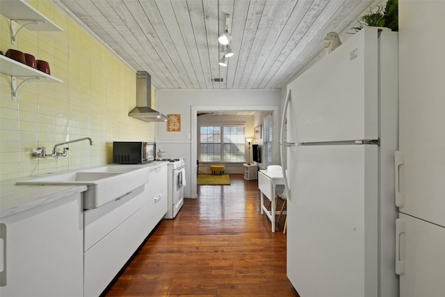 kitchen featuring tasteful backsplash, a sink, wall chimney range hood, white appliances, and dark wood-style flooring