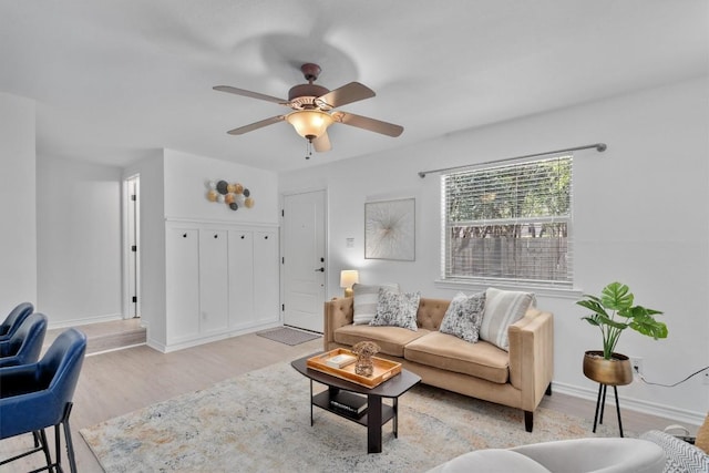 living area with light wood-style floors, ceiling fan, and baseboards