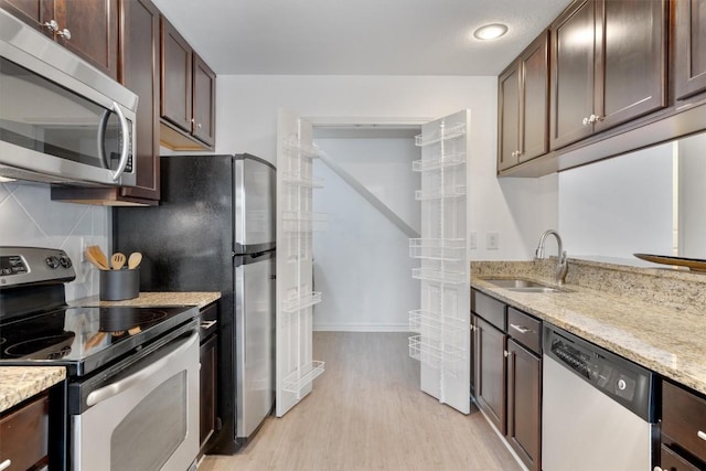 6700 Cooper Ln Unit 30, Austin, TX 78745 - kitchen with appliances with stainless steel finishes, light wood-style floors, dark brown cabinets, light stone countertops, and backsplash