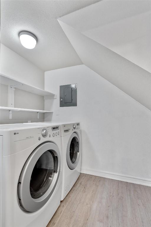 laundry area with washer and dryer, electric panel, and light wood-style floors