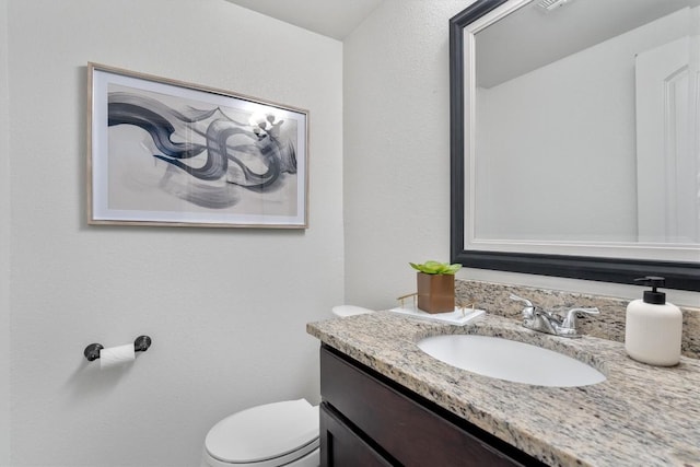 half bath featuring vanity and toilet