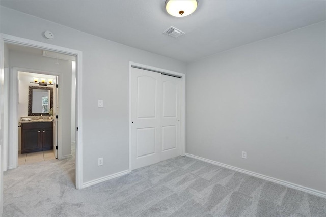 unfurnished bedroom featuring attic access, light carpet, a closet, and baseboards