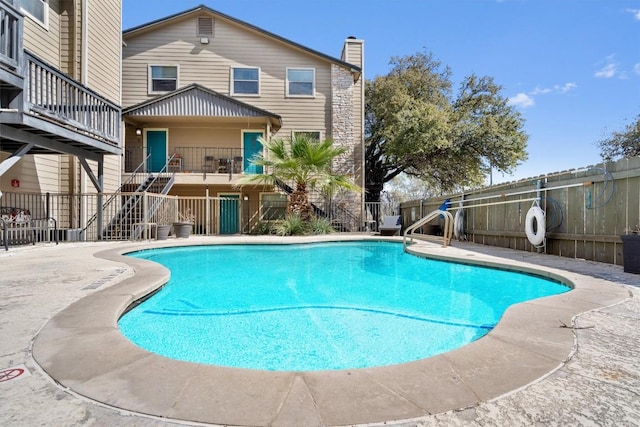view of swimming pool featuring fence and stairs