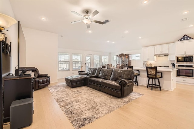 living room featuring light wood-style floors, a ceiling fan, visible vents, and recessed lighting