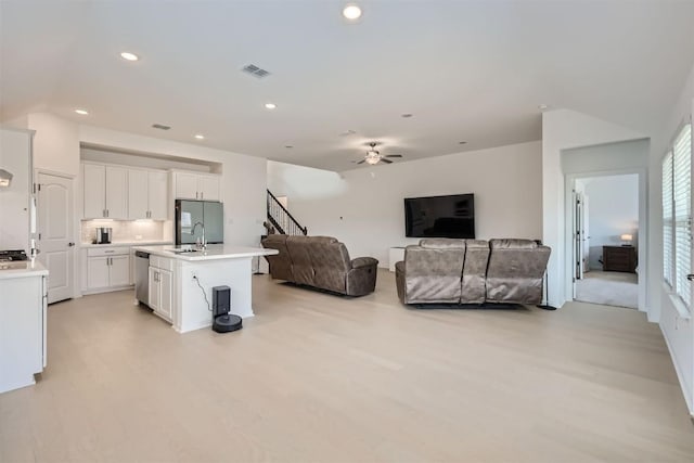 living area with a ceiling fan, vaulted ceiling, and light wood finished floors