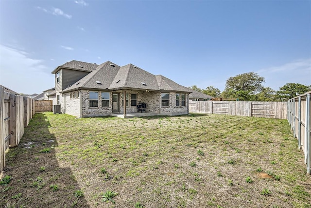 rear view of property with cooling unit, a yard, a fenced backyard, a patio area, and brick siding