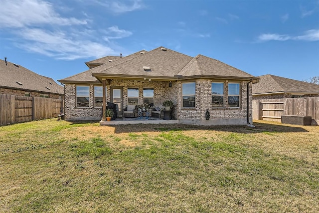 back of property featuring a patio area, a fenced backyard, brick siding, and a yard