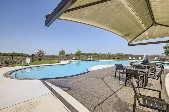 community pool with a patio area and a fenced backyard