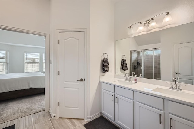 full bathroom featuring a shower stall, double vanity, a sink, and connected bathroom