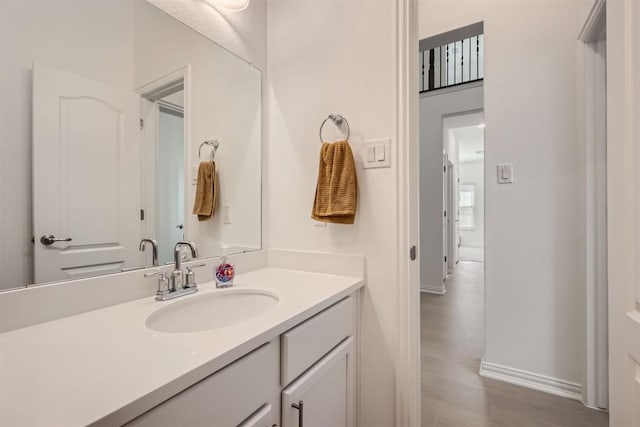 bathroom with wood finished floors, vanity, and baseboards