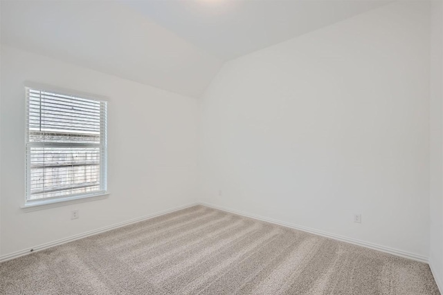 spare room with light colored carpet, baseboards, and lofted ceiling
