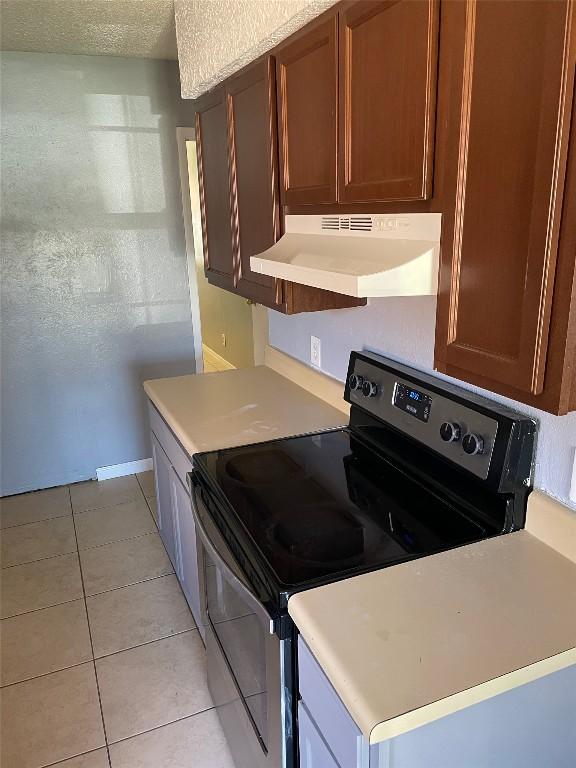 905 Fieldwood Dr, Austin, TX 78758 - kitchen with extractor fan, stainless steel range with electric stovetop, light tile patterned floors, and light countertops