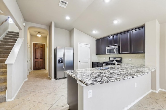 kitchen featuring visible vents, light tile patterned floors, light stone counters, a peninsula, and stainless steel appliances