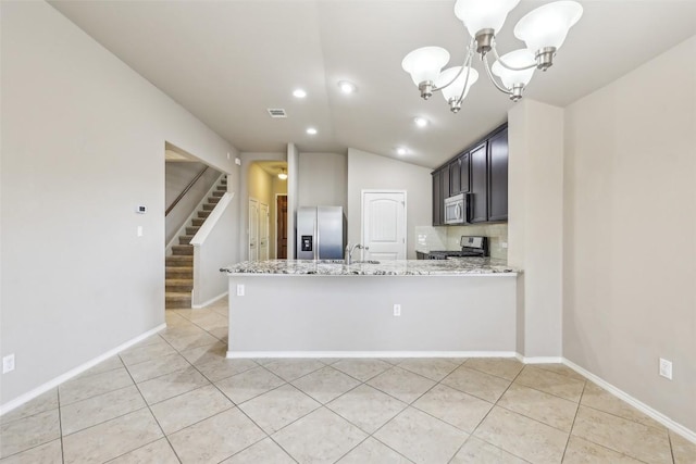 kitchen with light tile patterned flooring, light stone counters, a sink, a notable chandelier, and stainless steel appliances