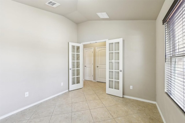 empty room with light tile patterned flooring, visible vents, french doors, and lofted ceiling