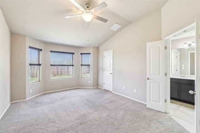 unfurnished bedroom with visible vents, light carpet, baseboards, a sink, and vaulted ceiling