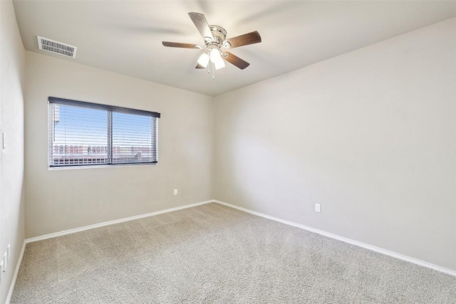 spare room with carpet floors, baseboards, a ceiling fan, and visible vents