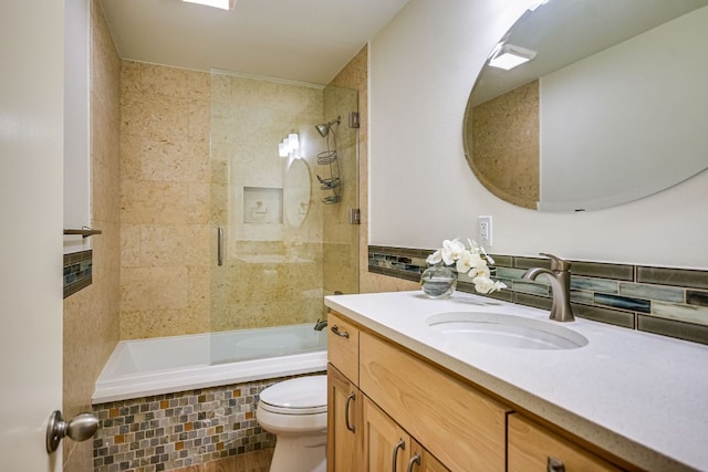 bathroom featuring vanity, tiled shower / bath, toilet, and tile walls
