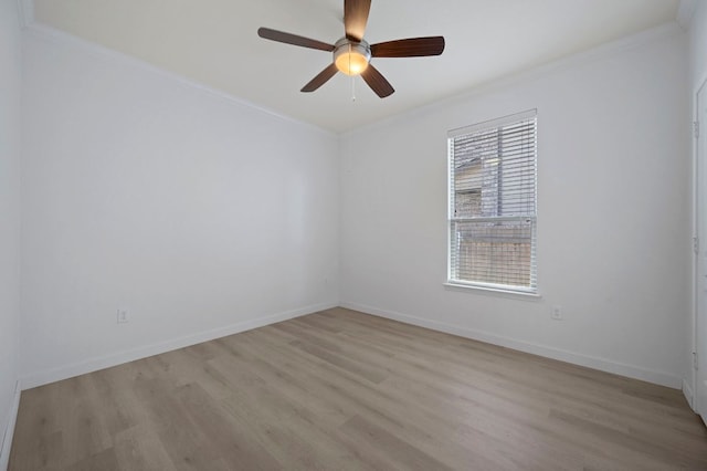 spare room featuring light wood finished floors, a ceiling fan, crown molding, and baseboards