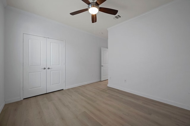 unfurnished bedroom featuring light wood finished floors, visible vents, baseboards, ornamental molding, and a closet