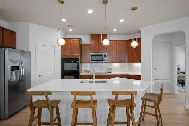 kitchen featuring visible vents, a sink, a kitchen breakfast bar, stainless steel appliances, and decorative backsplash