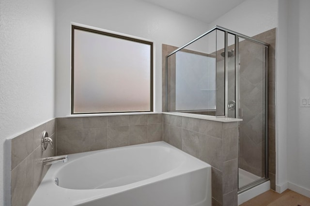 full bathroom featuring a bath, wood finished floors, and a stall shower