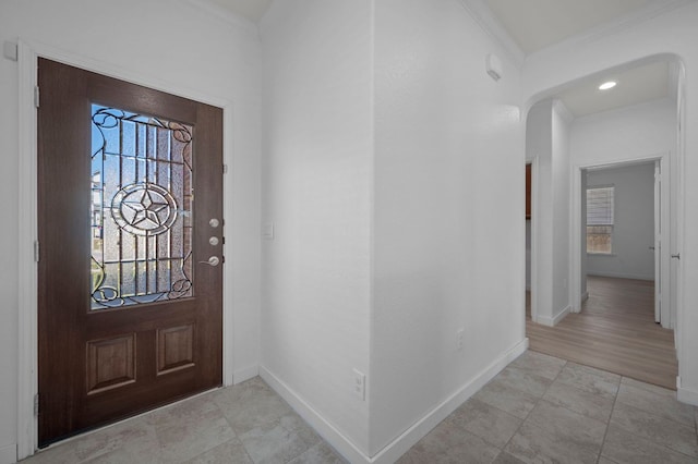 entrance foyer with arched walkways, crown molding, and baseboards