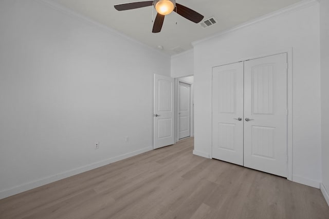 unfurnished bedroom with light wood-type flooring, visible vents, a closet, crown molding, and baseboards