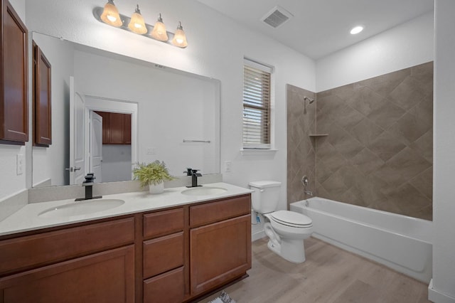 bathroom with toilet, wood finished floors, visible vents, and a sink