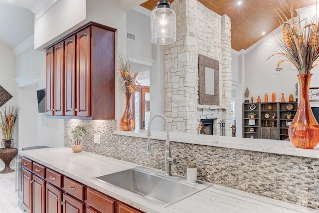 14904 Oak Shores Dr, Willis, TX 77318 - kitchen with a sink, reddish brown cabinets, a stone fireplace, decorative backsplash, and wooden ceiling