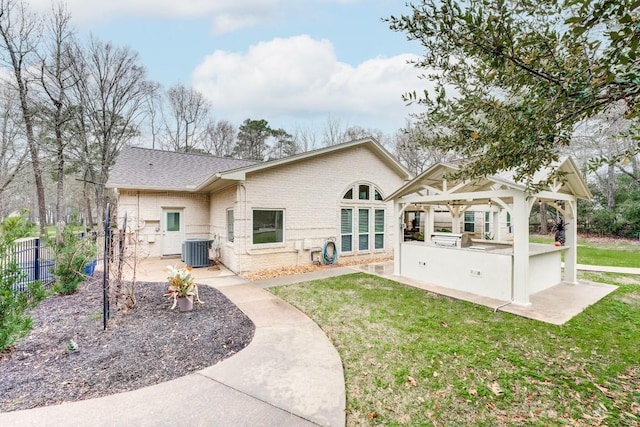 14904 Oak Shores Dr, Willis, TX 77318 - back of property featuring exterior kitchen, brick siding, cooling unit, and a yard