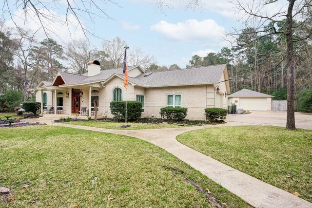 14904 Oak Shores Dr, Willis, TX 77318 - view of front facade with a porch, a front yard, a chimney, and a garage