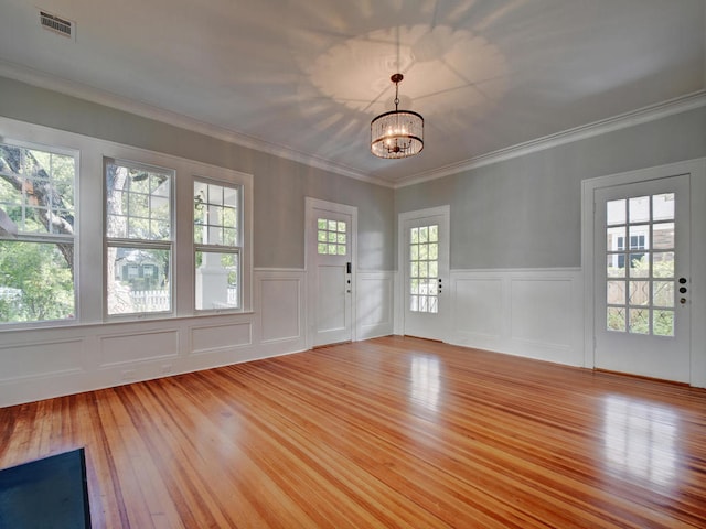 1203 W 22 1/2 St, Austin, TX 78705 - spare room with a chandelier, light wood finished floors, wainscoting, a decorative wall, and ornamental molding