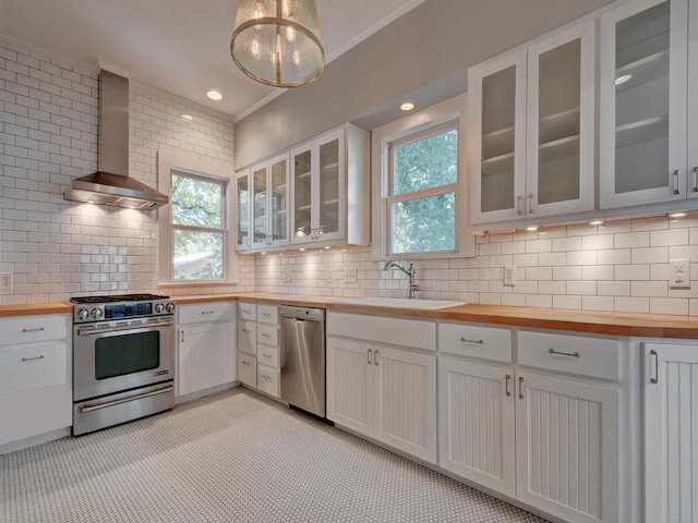 1203 W 22 1/2 St, Austin, TX 78705 - kitchen featuring butcher block countertops, stainless steel appliances, a sink, wall chimney exhaust hood, and ornamental molding