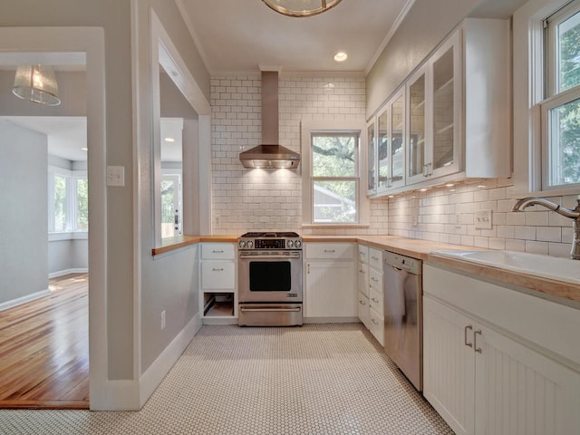 1203 W 22 1/2 St, Austin, TX 78705 - kitchen featuring stainless steel appliances, wall chimney range hood, a sink, healthy amount of natural light, and crown molding
