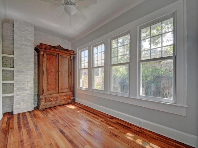 1203 W 22 1/2 St, Austin, TX 78705 - unfurnished room featuring healthy amount of natural light, light wood-style floors, ceiling fan, brick wall, and baseboards