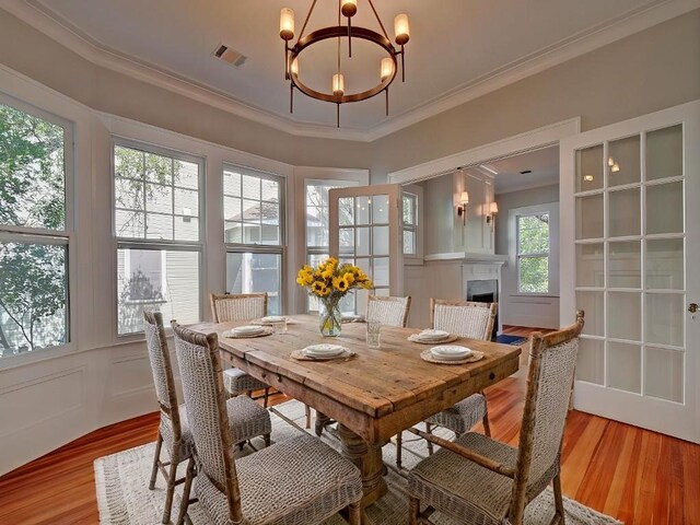 1203 W 22 1/2 St, Austin, TX 78705 - dining room featuring crown molding, a chandelier, light wood-style flooring, and a fireplace