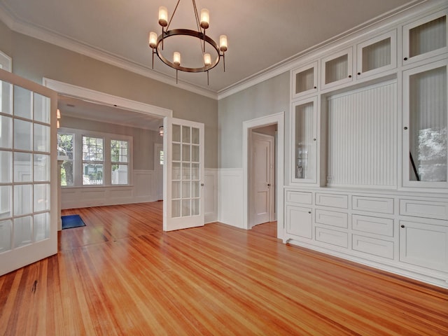 1203 W 22 1/2 St, Austin, TX 78705 - unfurnished dining area with french doors, a chandelier, light wood-style flooring, ornamental molding, and wainscoting