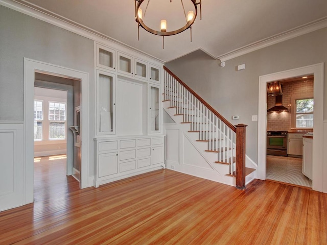 1203 W 22 1/2 St, Austin, TX 78705 - stairs featuring wood finished floors, crown molding, a chandelier, a decorative wall, and wainscoting