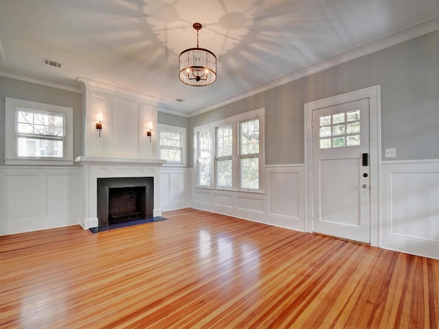 1203 W 22 1/2 St, Austin, TX 78705 - unfurnished living room with a decorative wall, a chandelier, a fireplace with flush hearth, light wood-style floors, and ornamental molding
